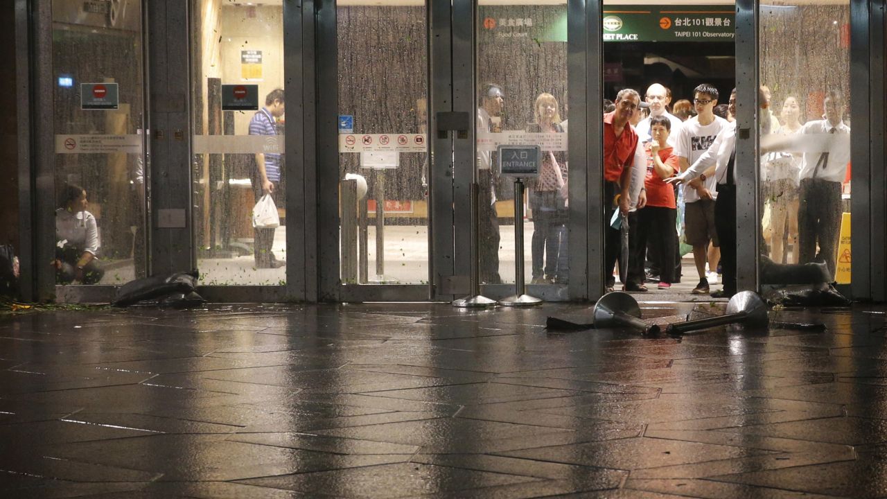 People are held back by security until winds from Typhoon Dujuan ease at the damaged entrance to the Taipei 101 building in Taipei on Monday, September 28.