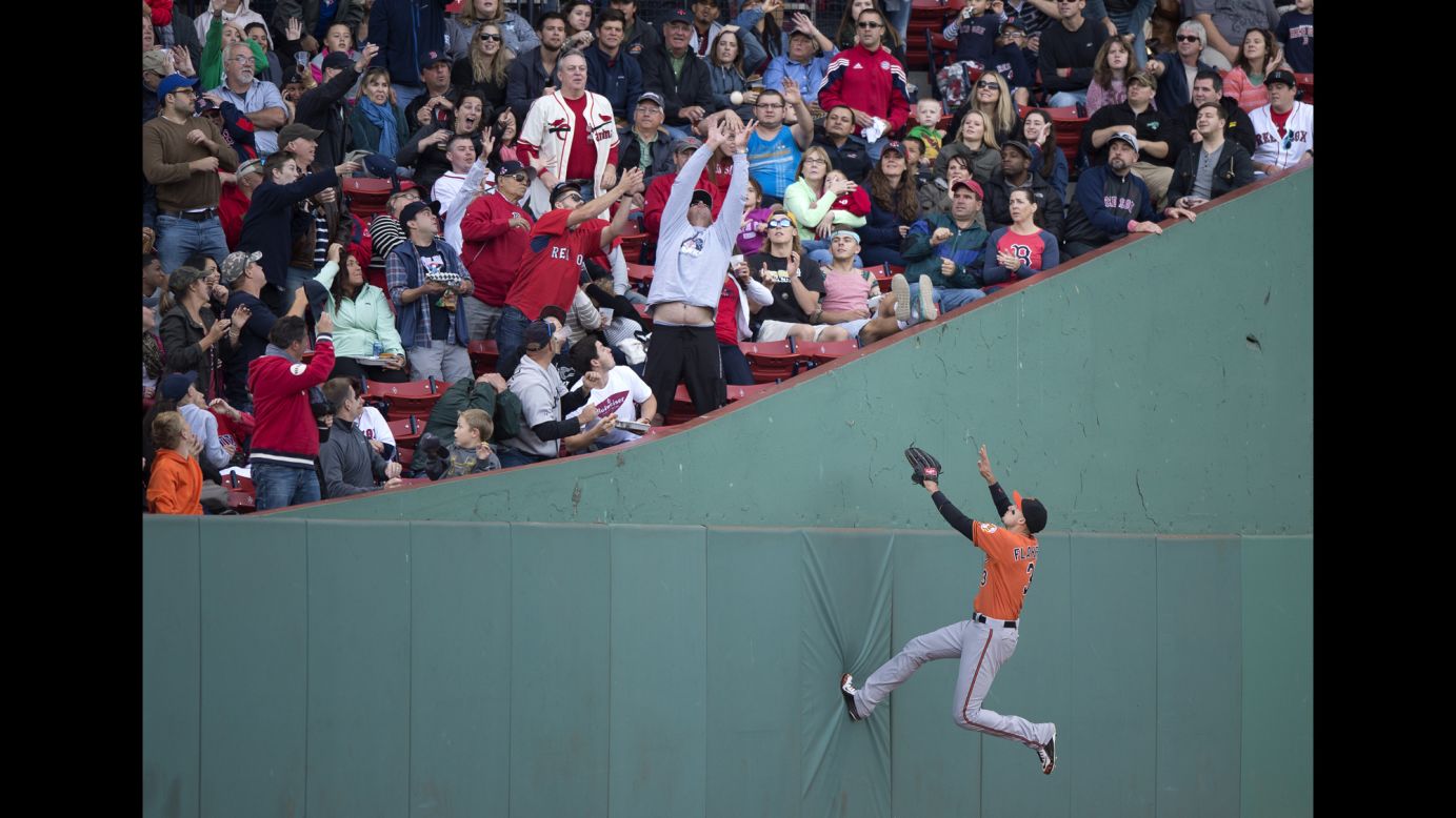 Baltimore's Ryan Flaherty jumps on the left-field wall while chasing a foul ball Saturday, September 26, in Boston.