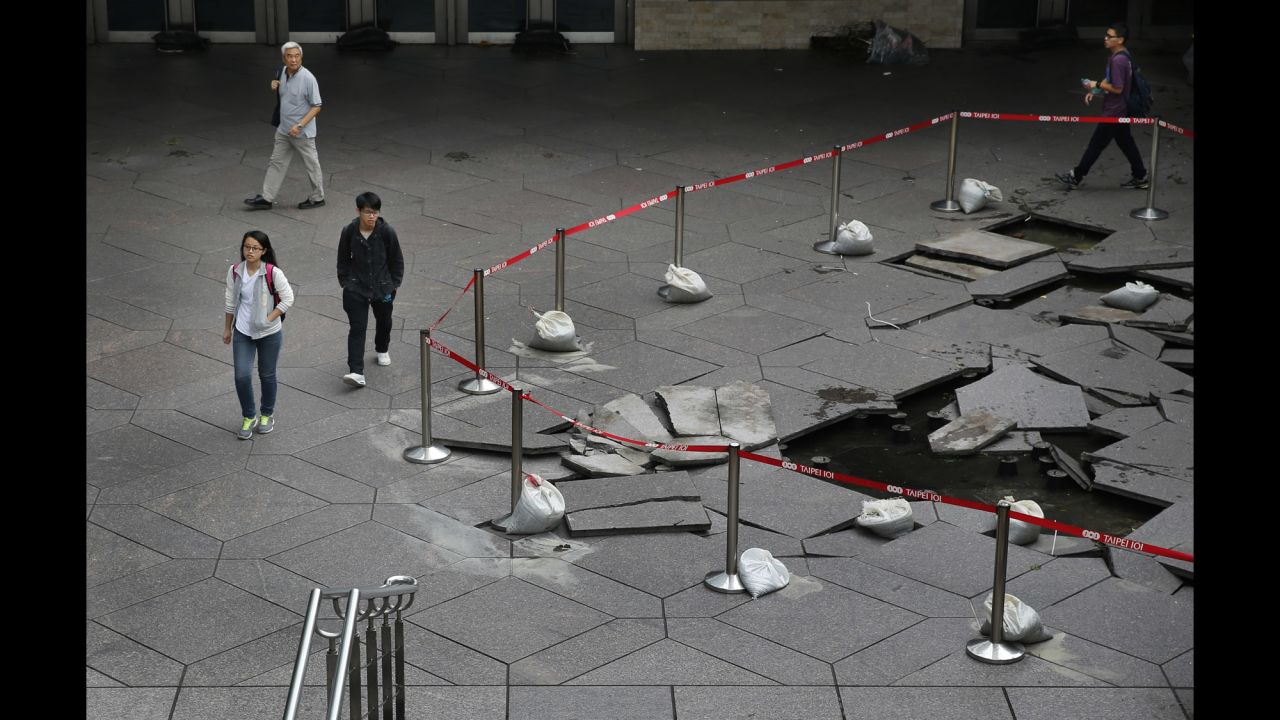 Pedestrians walk past floor tiles damaged by falling debris from Dujuan in the business district of Taipei on September 29. 