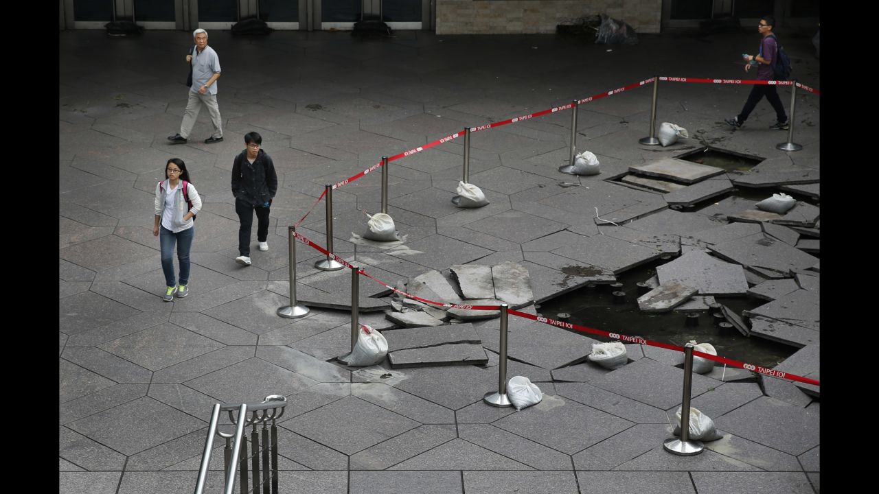 Pedestrians walk past floor tiles damaged by falling debris from Dujuan in the business district of Taipei on September 29.