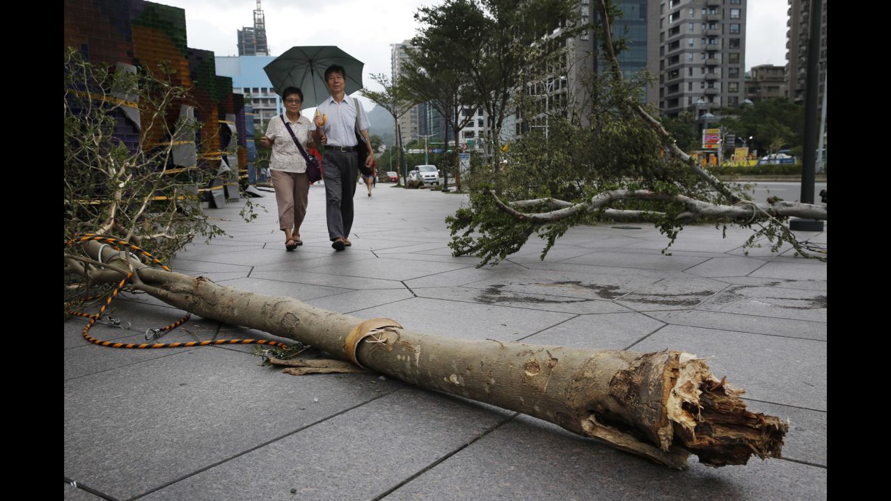A couple walks through fallen trees in the business district of Taipei, Taiwan, on Tuesday, September 29. Typhoon Dujuan made landfall near the border of Hualien and Yilan counties in northeast Taiwan just after 5 p.m. Monday.