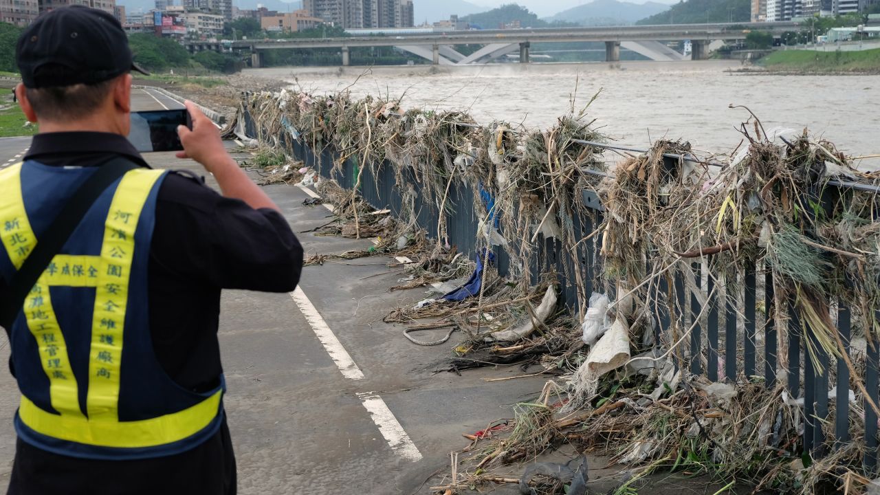 A security guard takes a photo of debris on the banks of the Xindian River in New Taipei City on September 29.