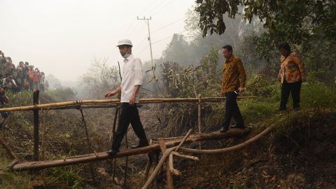 Indonesia's President Joko Widodo, in white, inspects a firefighting operation on burning peatland in Borneo.