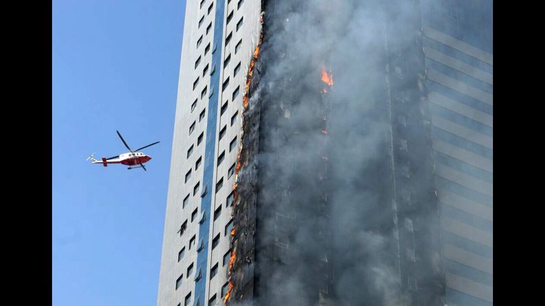 A helicopter flies near a skyscraper that caught fire in Sharjah, United Arab Emirates, on Thursday, October 1. It was not immediately clear whether there were any casualties.