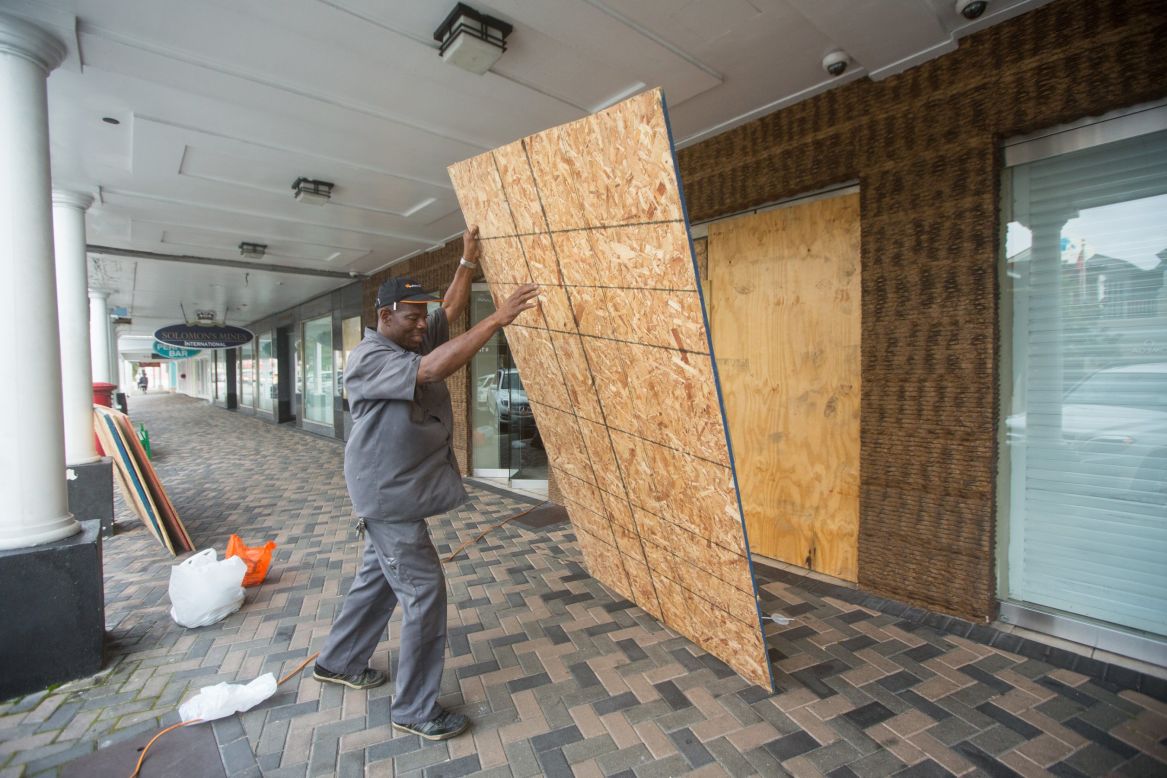 A man in Nassau puts up plywood shutters to cover store windows on Thursday, October 1.
