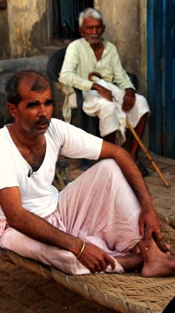 Ombir Sisodia, the father of one of the arrested suspects, sits in his yard. He denies his son's involvement in the assault.