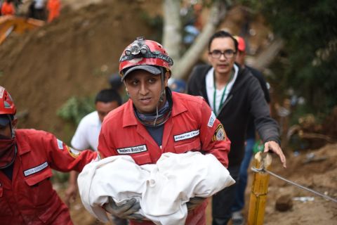 A rescuer carries the body of a child recovered from the mud and debris on October 2.
