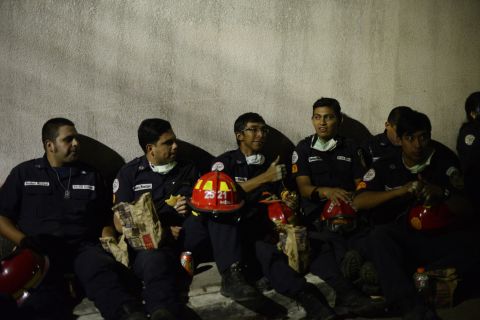 Municipal firefighters rest during rescue operations on October 2. 