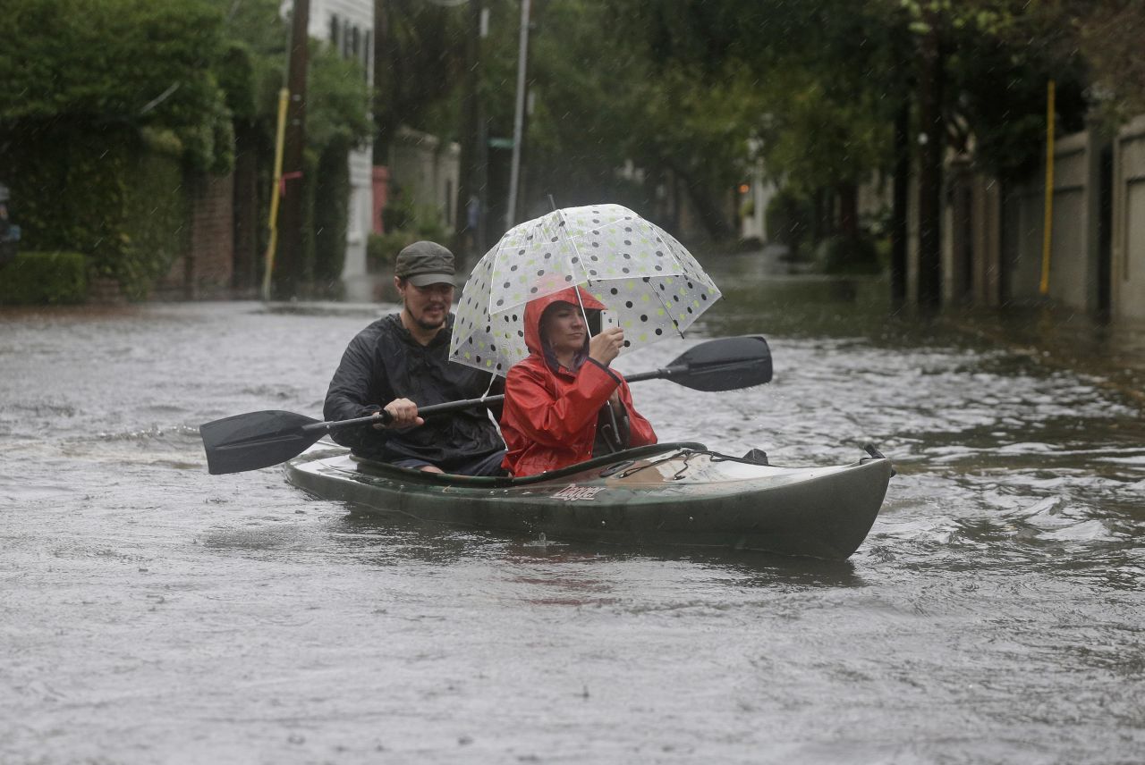 Paul Banker paddles a kayak as his wife, Wink Banker, takes photos on a flooded street in Charleston, South Carolina, on October 3. 