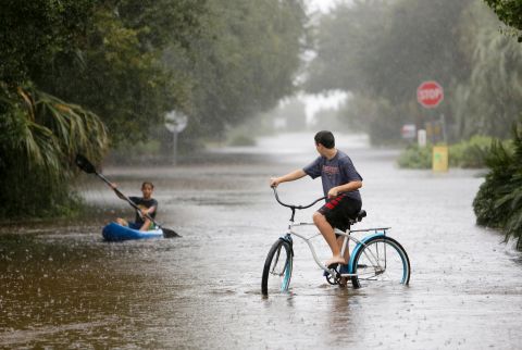 Will Cunningham, 14, rides his bike down Station 29 on Sullivan's Island, South Carolina, ahead of his paddling  friend Patrick Kelly, 14, on October 3. 
