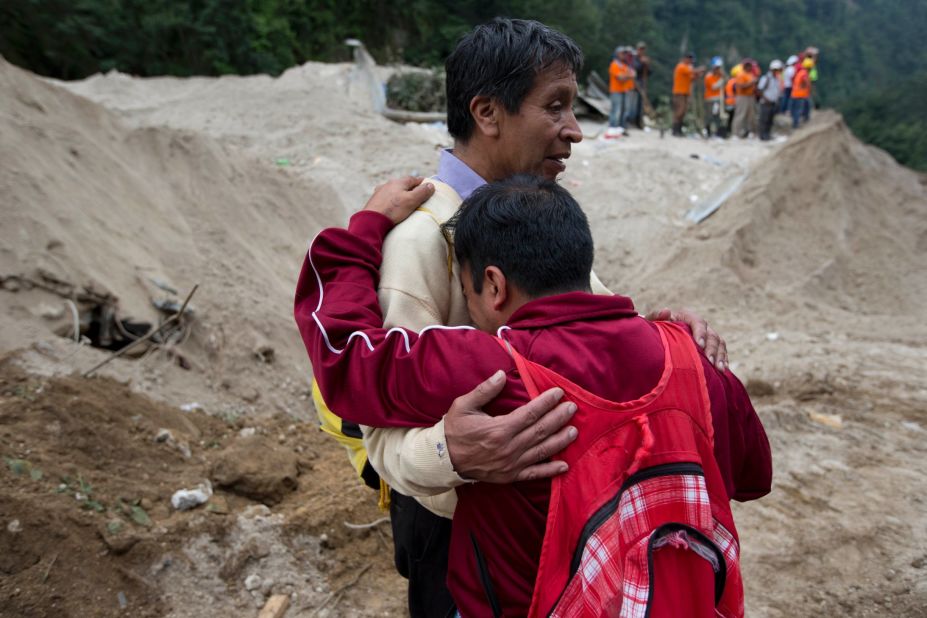 Neighbors comfort each other as rescue workers continue the search for townspeople on October 3. 