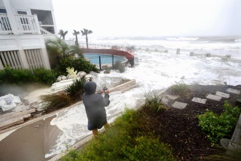 Bob Ashbaugh, from Pittsburgh, takes video of waves crashing over homes at risk from erosion during high tide in Isle of Palms, South Carolina, on October 3. 