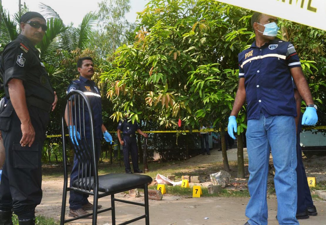 Bangladeshi police officials stand guard at the site where a Japanese citizen was shot to death by attackers in Rangpur on October 3, 2015. 
