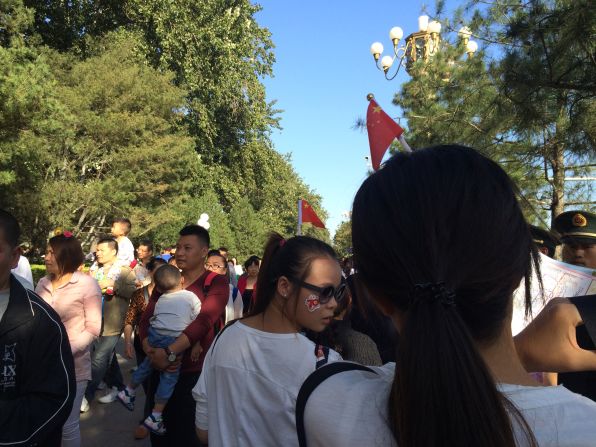 Two girls wearing Chinese flag clips in their hair wait in line to visit Tiananmen Square and the Forbidden City in Beijing on October 2.