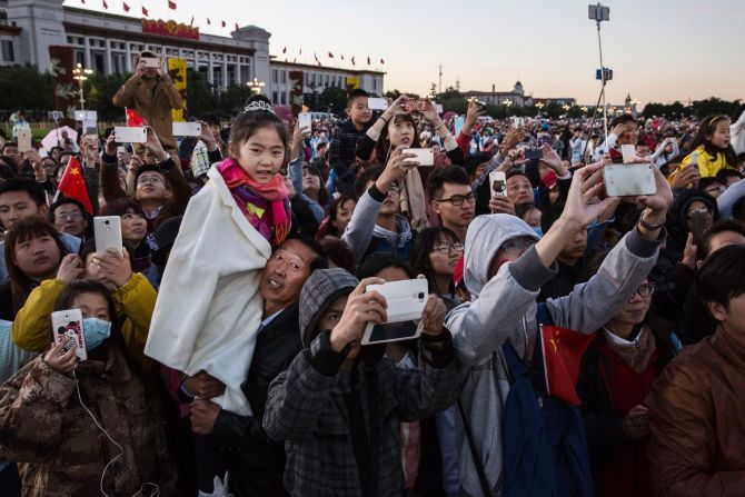 Crowds of excited onlookers break out their phones and "selfie sticks" to snap pictures during the official flag-raising ceremony on October 1, at Tiananmen Square, the second most visited place in the country according to state broadcaster CCTV. 