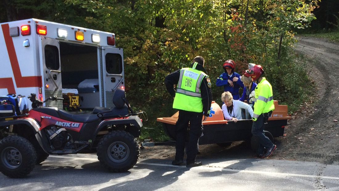 Emergency first responders assist a woman as she is transferred to an ambulance. 