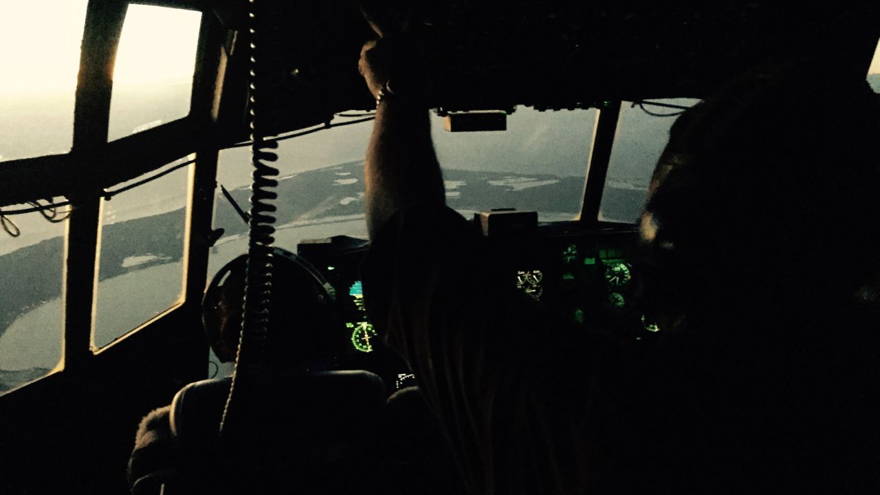When the HC-130 first took off, the cockpit was dark, the instruments on the control panel offering the only light. Here, the first rays of sun gleam into the cockpit as Lt. Janelle Setta, a copilot, left, and Fielder, the engineer, guide the plane to the search area.