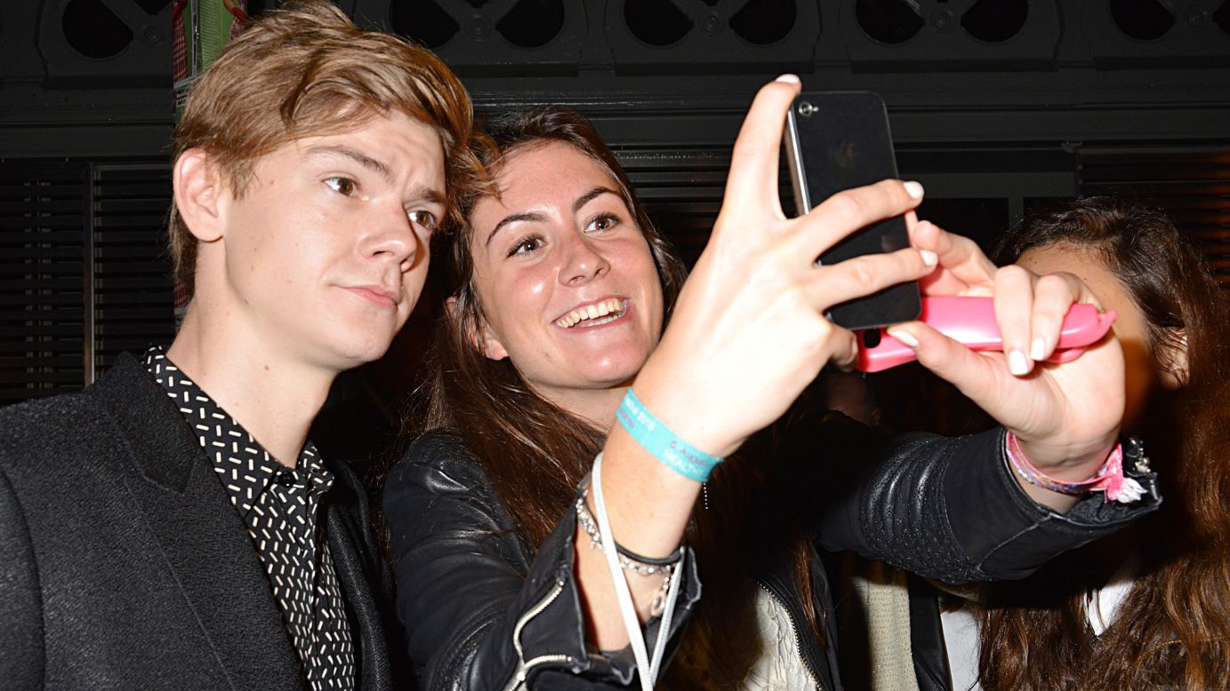 Actor Thomas Brodie-Sangster poses for a fan's photo while attending a show at Paris Fashion Week on Monday, October 5.