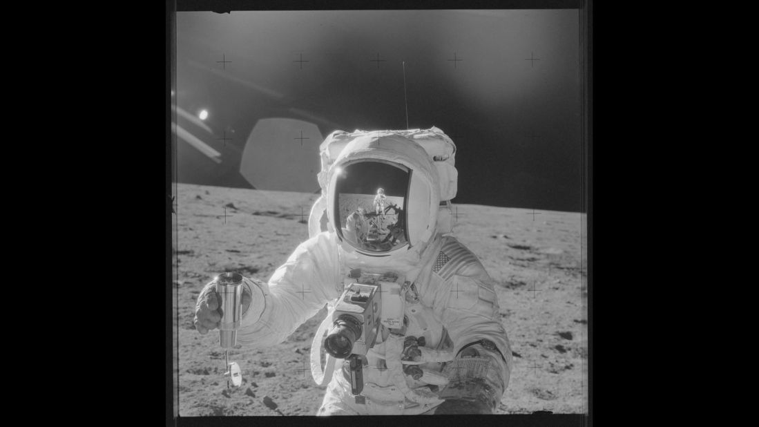 Astronaut Alan Bean holds a sample of lunar soil during Apollo 12. Pete Conrad's reflection can be seen in Bean's visor as he takes the photo.