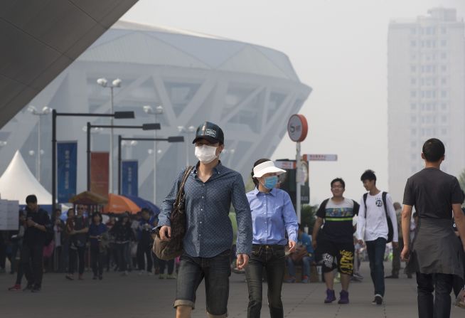 Tennis fans protecting themselves from pollutants walk past the National Tennis Stadium during the China Open tennis tournament in haze-hit Beijing on October 5.