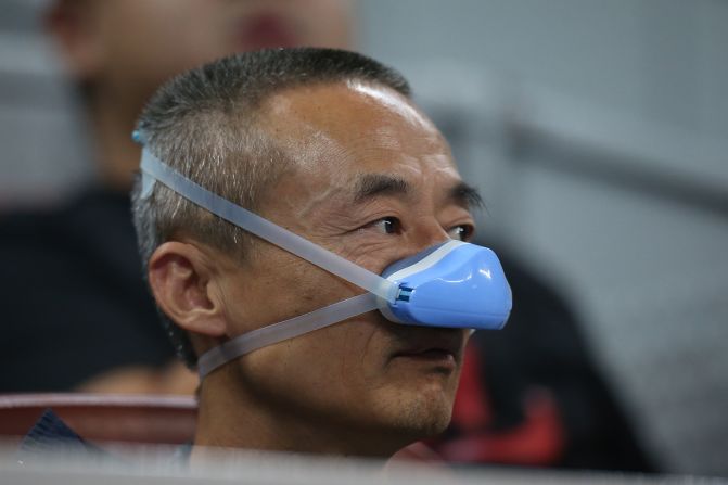 A man shields his nose from the smog during the match between Belinda Bencic of Switzerland and Madison Brengle of the United States at the National Tennis Stadium on October 5, 2015.