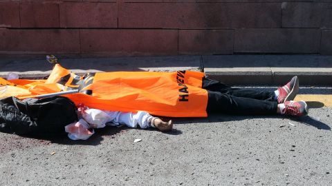 The body of a victim is covered with a flag.