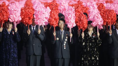 North Koreans hold decorative flowers during the parade.