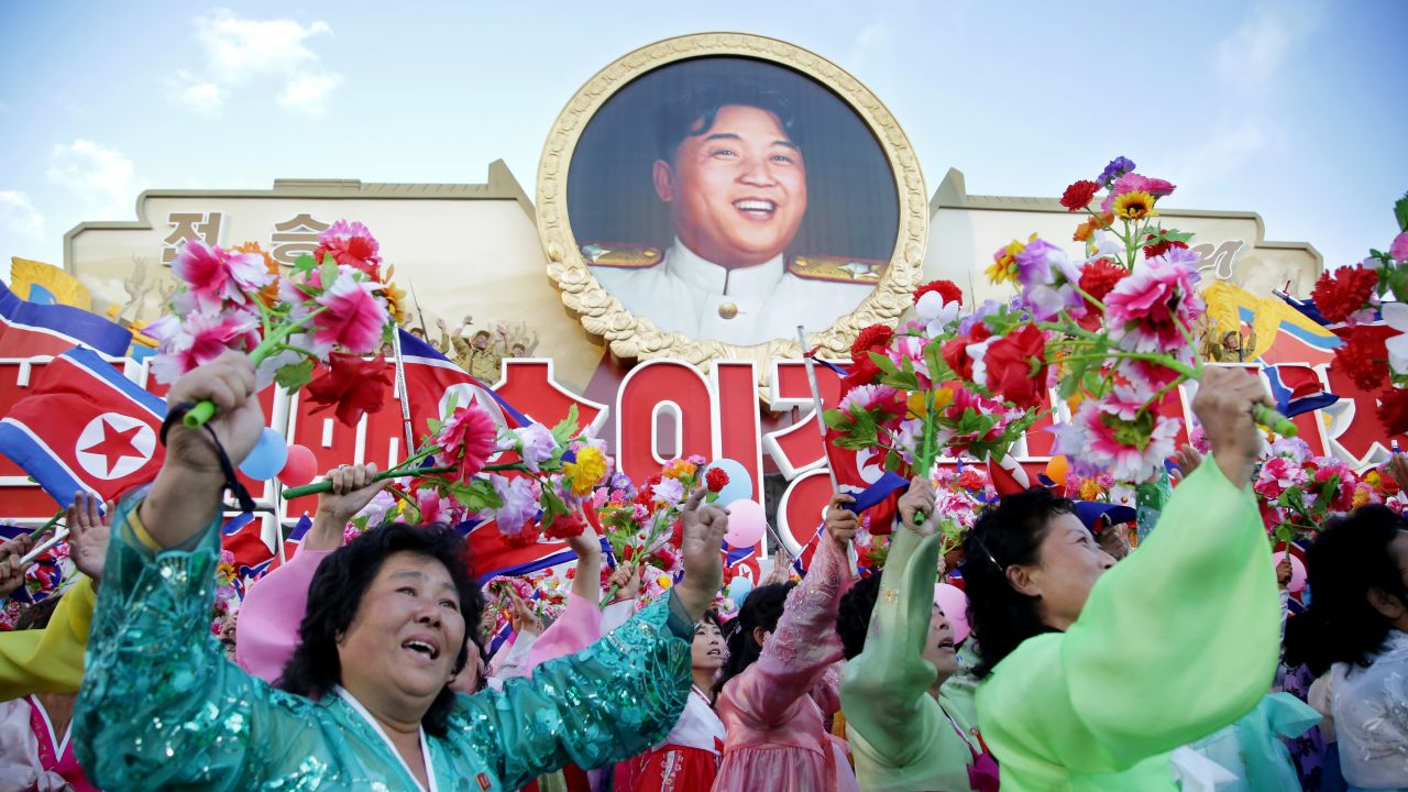 North Koreans parade beneath a portrait of leader Kim Jong Un.