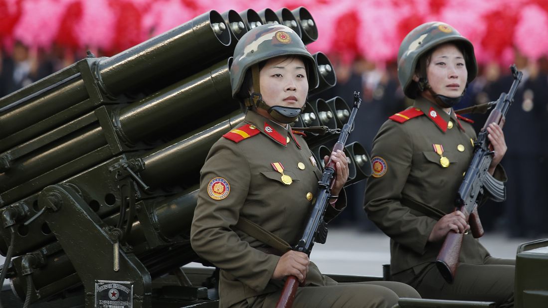 Two North Korean soldiers ride a military vehicle through Kim Il Sung Square.