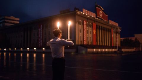 A volunteer holds burning torches at Kim Il Sung Square.