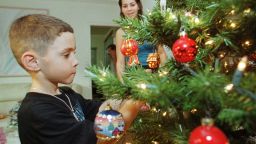 MIAMI, FL - DECEMBER 22:  Elian Gonzalez (L) decorates a Christmas tree with his cousin Marisleysis Gonzalez at her home in Miami 22 December, 1999, after finding out that immigration officials have delayed a hearing to decide the six-year-old's fate to 21 January, 2000. Elian has been living with his cousin and great uncle in Miami since he was rescued at sea 25 November. The boy's mother and several others died when the boat they were in sank as they attempted to reach the US from Cuba. His family is currently in a custody fight with his father in Cuba.  (Photo credit should read BILL COOKE/AFP/Getty Images)