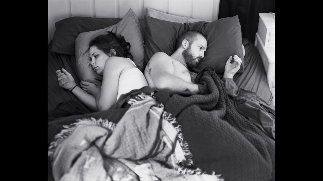 Photographer Eric Pickersgill and his wife, Angie, pose without their cell phones in bed. Eric's photo series "Removed" explores how people focus on our phones even while in the presence of others, often to our social and physical detriment. He asks his subjects to pose with their phones and then slip them from their hands for a photo.