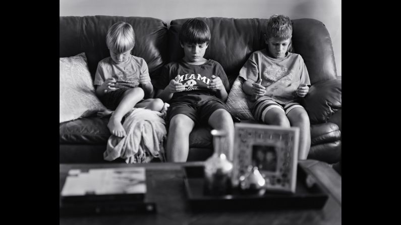 Boys gather on the sofa to play with their hand-held devices. 