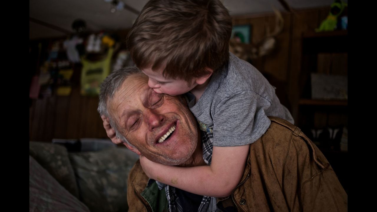 Skylor Cox, 3, jumps on his the back of his father, Faron, to give him little kisses at their home in Fordsville, Kentucky, in February 2014.