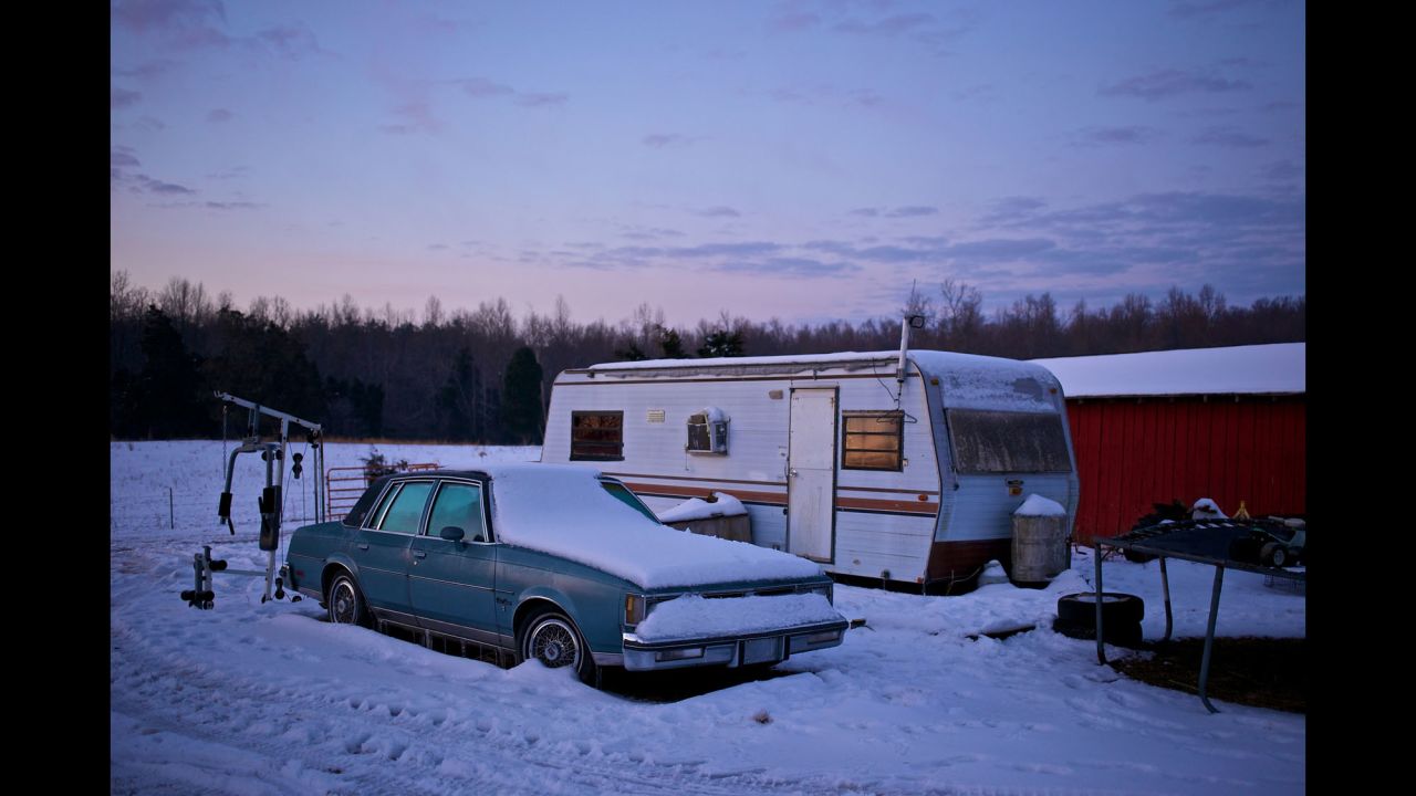 A car and an abandoned trailer sit on Faron Cox's property at sunrise.