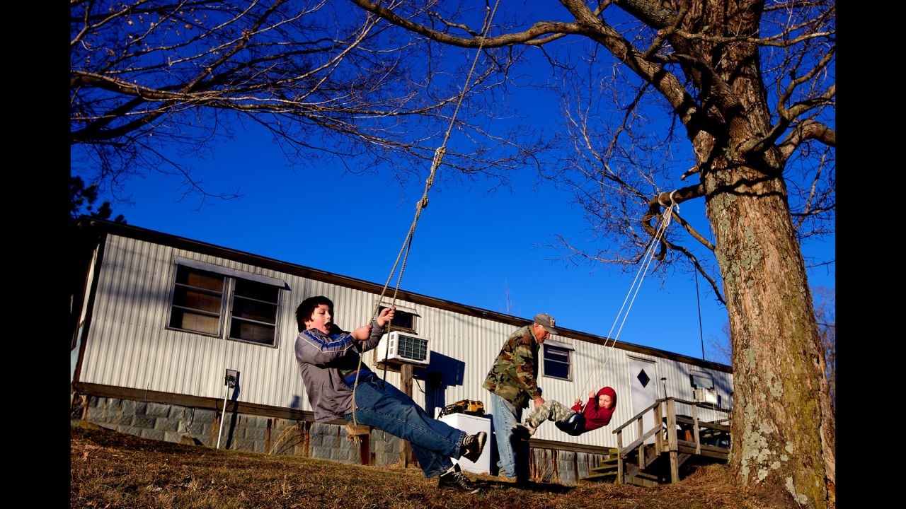 Faron Cox Jr., 7, and Skylor Cox, 3, play on rope swings outside of their home. "When I first had my first three kids, back in the 70s, I thought that was it," Faron Cox Sr. said. "I wasn't thinking about having another wife or more kids and then more kids. It never entered my mind."