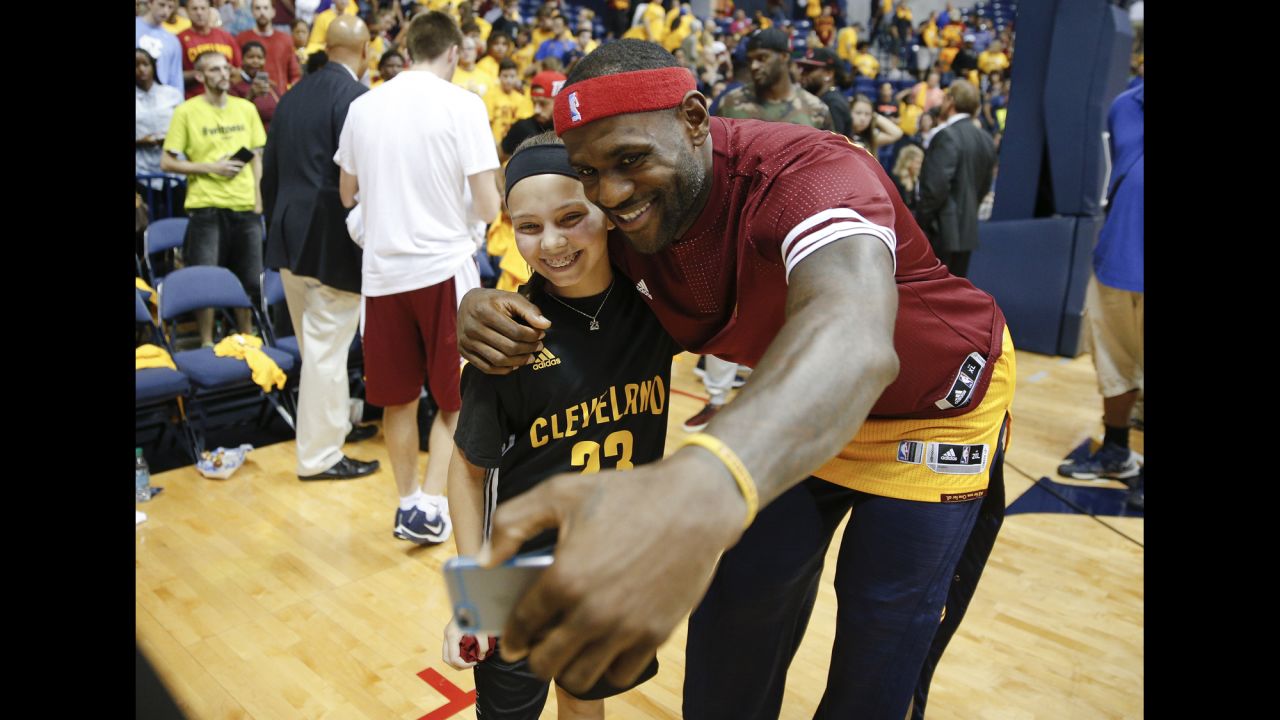 Basketball star LeBron James takes a photo with a young fan after an NBA preseason game in Cincinnati on Wednesday, October 7.