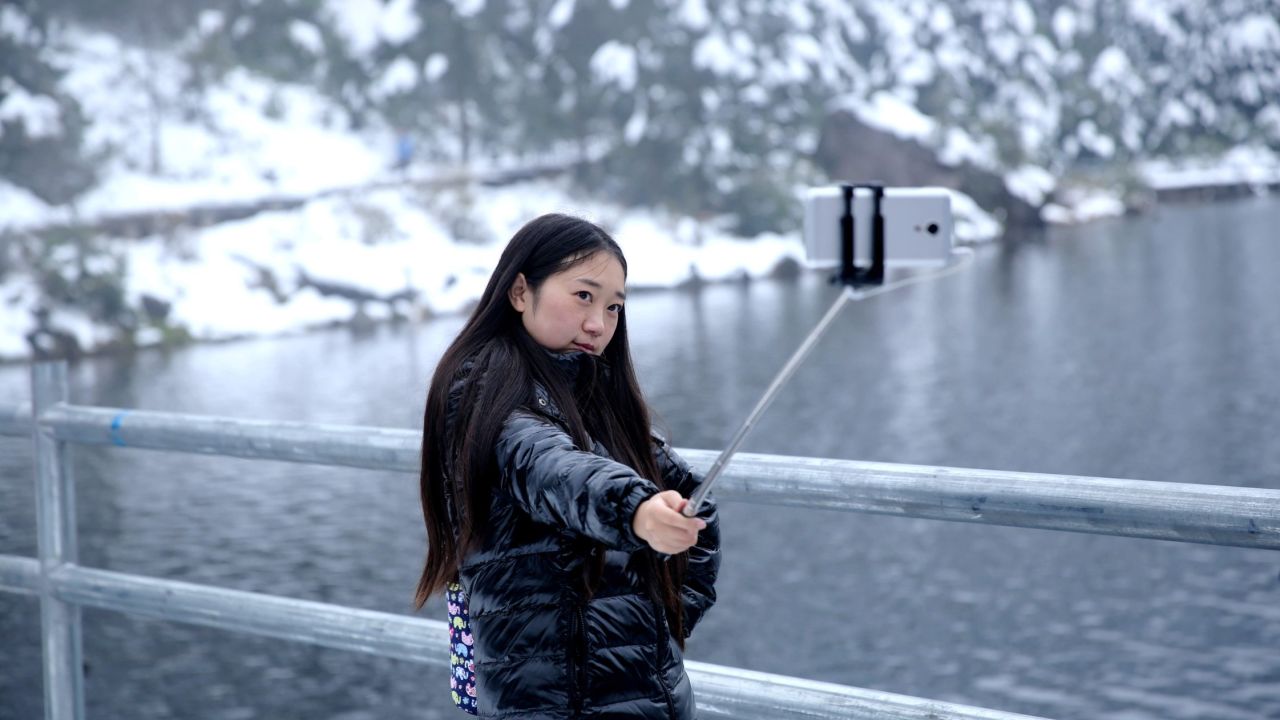 A woman uses a selfie stick at Luoji Mountain after a heavy snow in Puge County, China, on Monday, October 12.