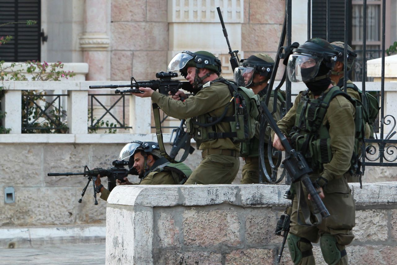 Israeli soldiers aim their weapons toward Palestinian protesters during clashes in Bethlehem on October 12.