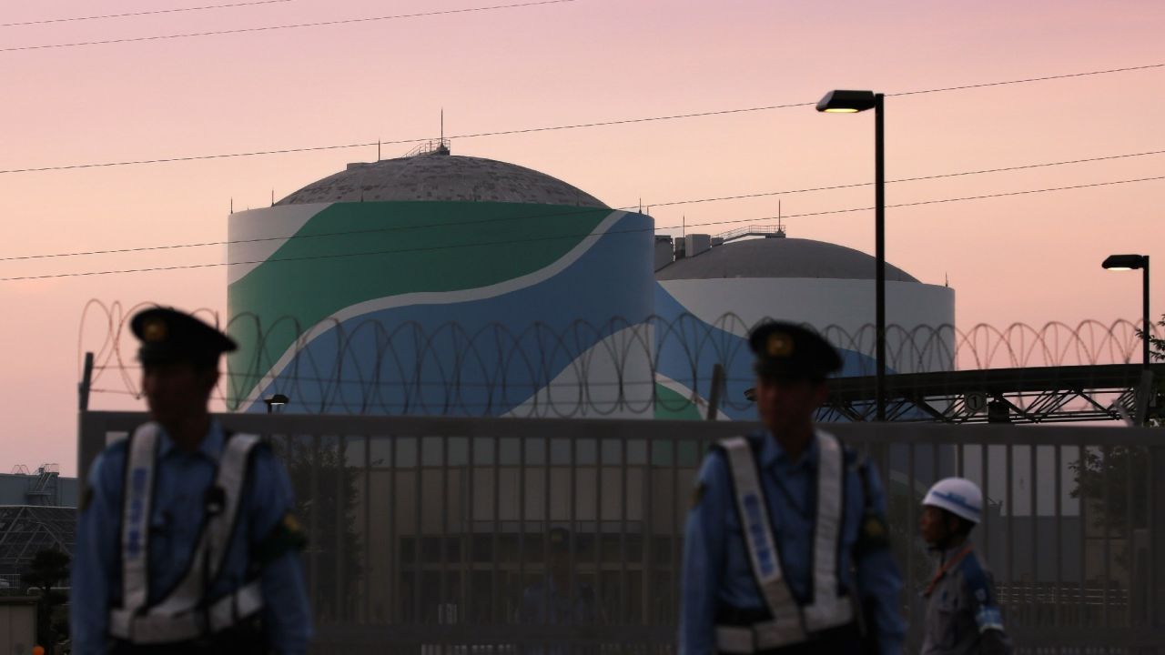 Nuclear reactor buildings of the Kyushu Electric Power Sendai nuclear power plant are seen behind police officers standing guard in the twilight in Satsumasendai in Kagoshima prefecture, on Japan's southern island of Kyushu on August 11, 2015.
