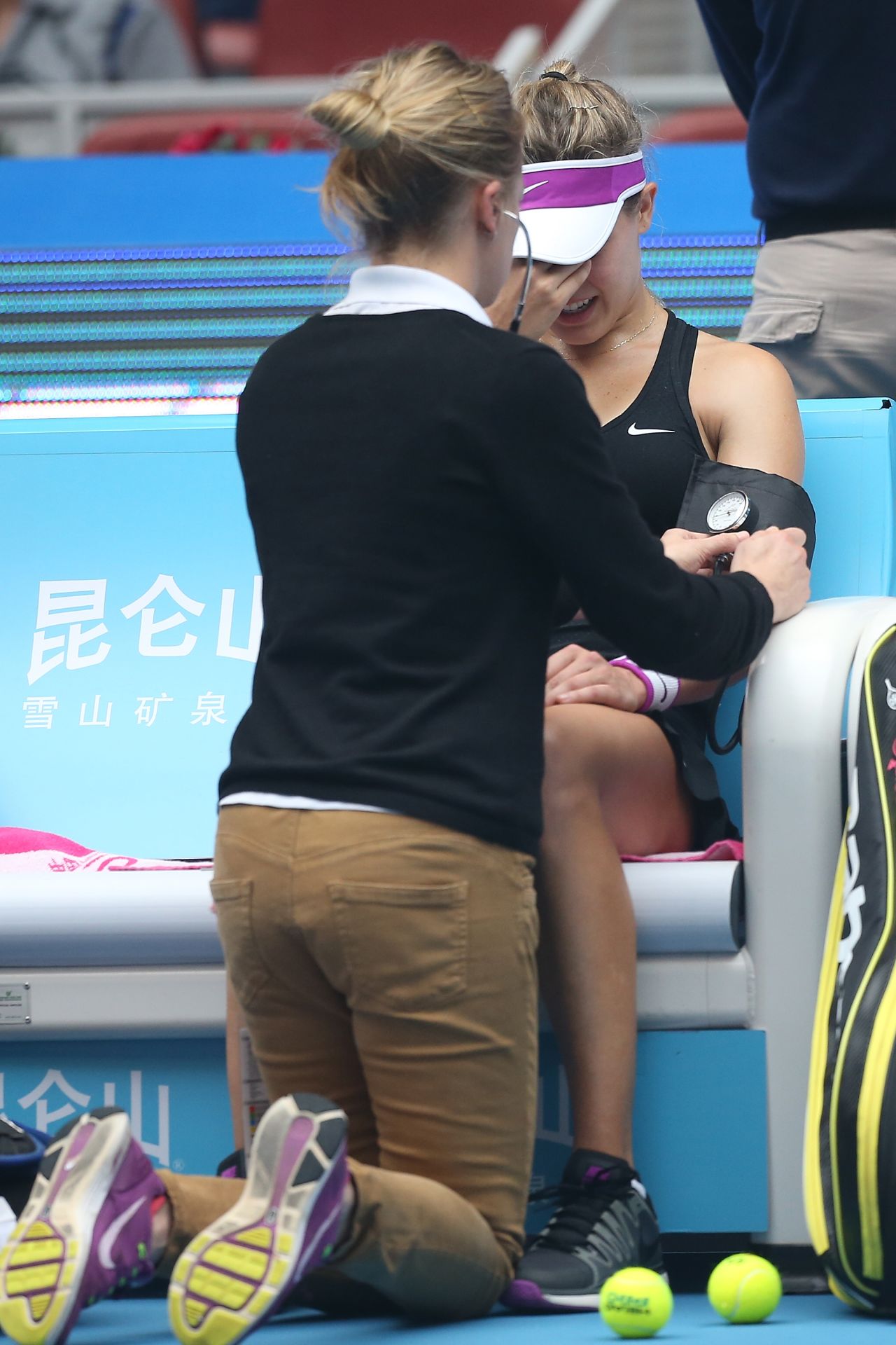 A visibly distressed Bouchard is pictured receiving treatment on court at the China Open before her retirement.