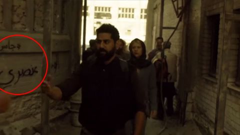 Danes as Carrie Mathison walking through a fictional Syrian refugee camp past the graffiti slogan: "Homeland is racist."
