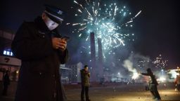 BEIJING, CHINA - February 19: A Chinese security guard checks his smartphone as fireworks explode during celebrations of the Lunar New early on February 19, 2015 in Beijing, China.The Chinese Lunar New Year of Sheep also known as the Spring Festival, which is based on the Lunisolar Chinese calendar, is celebrated from the first day of the first month of the lunar year and ends with Lantern Festival on the Fifteenth day. (Photo by Kevin Frayer/Getty Images)