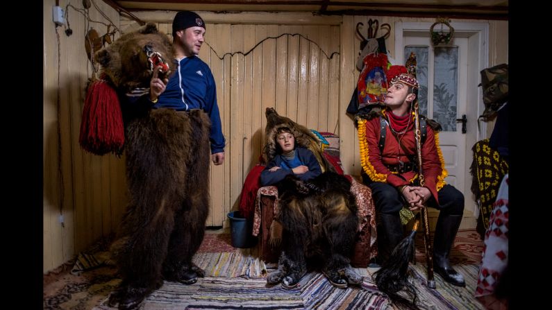 Catalin Apetroaie chats with a young bear and the "bear tamer" seated on his porch. They and the rest of the troupe have just finished performing for a family and are taking a rest before they continue on to the homes of other patrons.