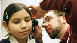 CICERO, IL - FEBRUARY 22:  Fourth-grader Arylu Paniagua, 9, receives an ear exam from Dr. Michael Paul during a physical in the Loyola Pediatric Mobile Health Unit, parked outside Columbus West Elementary School, February 22, 2005 in Cicero, Illinois. The Loyola Pediatric Mobile Health Unit, the first "doctor's office on wheels" in the Midwest which provides free medical care to underserved and uninsured children, reached its 1,500 clinic visit in the community with this stop. The unit, the first if its kind in the world, serves as a national model for other children's hospitals and started traveling in the fall of 1998 with one community partner and now has 350 community partners in the Chicago area.  (Photo by Tim Boyle/Getty Images)