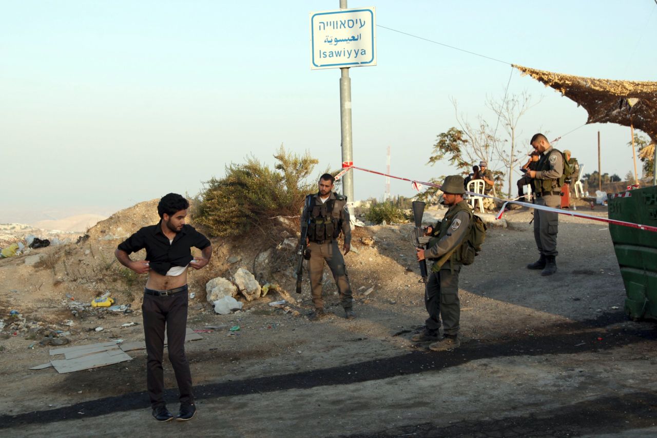 Israeli border police order a Palestinian to lift his shirt at a checkpoint as he exits the Arab neighborhood of Issawiyeh in Jerusalem on October 17.