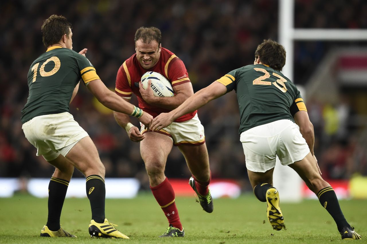 Wales' centre Jamie Roberts (C) runs with the ball  as South Africa's fly half Handre Pollard (L) and South Africa's centre Jan Serfontein (R) wait to tackle.
