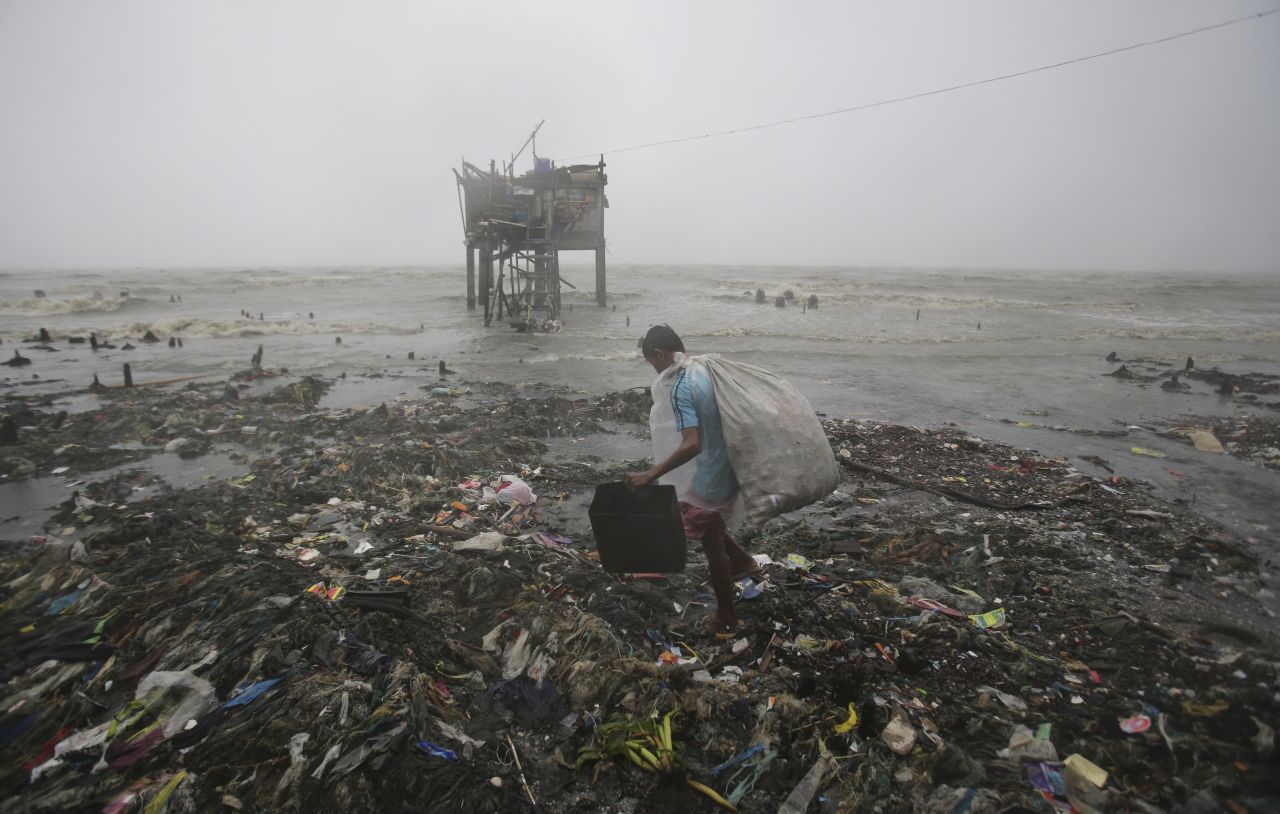 A man scavenges recyclable materials near a house on stilts as strong winds and rains hit the coastal town of Navotas on October 18.