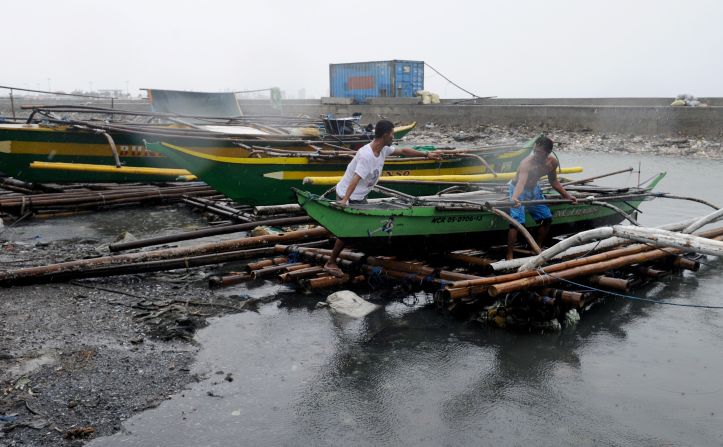Fishermen move outrigger boats to higher ground along the coastal area of Manila Bay on October 18.  The coast guard banned sailing.