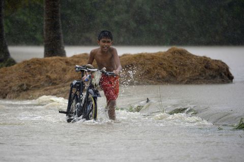 A child pushes his bicycle as he crosses a flooded street in Ineangan after the Magat River swelled.